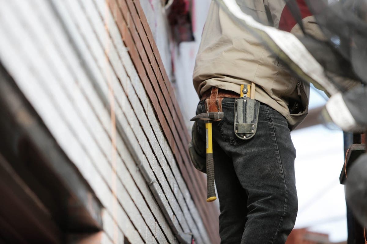A carpenter in canvas work pants kneeling on a job site